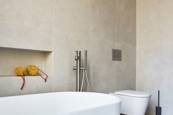 Salle de bains design rénovée à Vevey. Carrelage gris et mobilier sanitaire blanc. Niche encastrée en carrelage