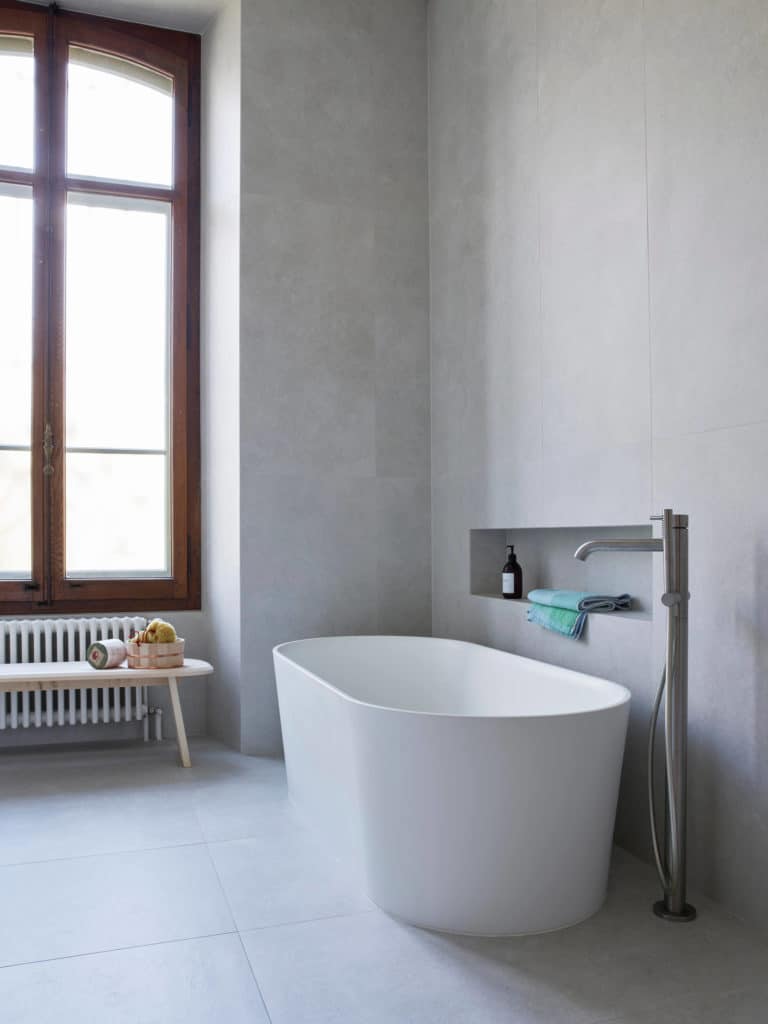 Salle de bains rénovée avec carrelage de couleur grise au mur et au sol.
