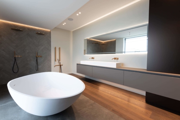Salle de bains avec carrelage grands formats gris au sol et carrelage en chevrons gris au mur, double douche italienne et baignoire 2 places blanches