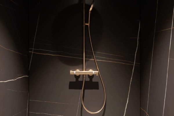 Douche italienne et carrelage grand format dans une maison au bord de l'eau à Rolle. Carrelage imitation marbre et sanitaire doré