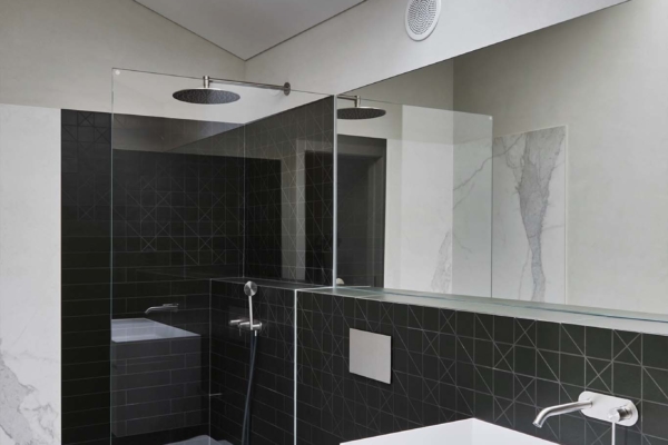 Carrelage dans une salle de bain design, douche italienne avec carrelage imitation marbre. Velux offrant une lumière naturelle