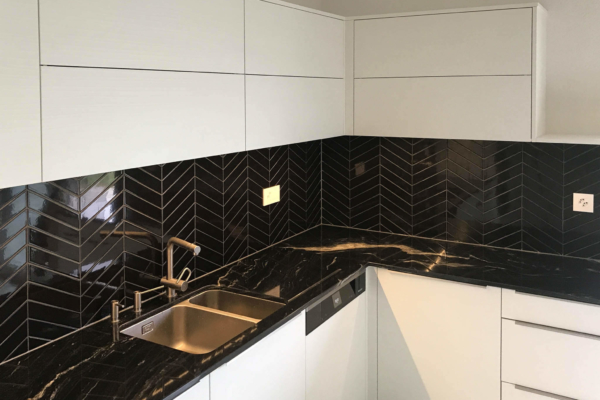 Cuisine en carrelage noire. Armoire blanche et plan de travail en marbre