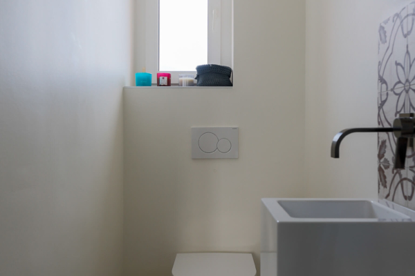 Toilettes avec wc blanc carrelage avec motif au sol et fenêtre au sol