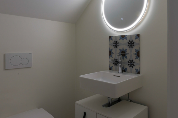 Toilettes avec wc blanc carrelage avec motif au sol, meubles blanc et peinture au mur