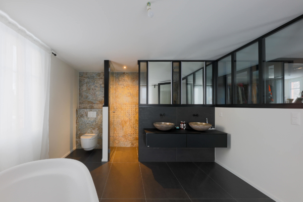 Salle bains avec un sol en carrelage noir et un carrelage à motif au mur lumière allumée