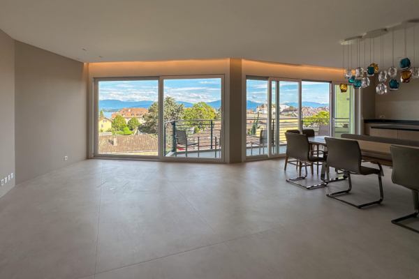 Séjour lumineux avec carrelage imitation béton, grandes fenêtres donnant sur le lac Léman et les montagnes, dans une rénovation d'appartement à Nyon