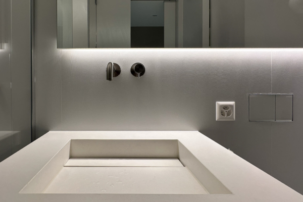 Lavabo moderne avec robinetterie murale en acier inoxydable et fond de mur texturé en carrelage Iris Ceramica Luce en gris clair, design épuré, à Nyon