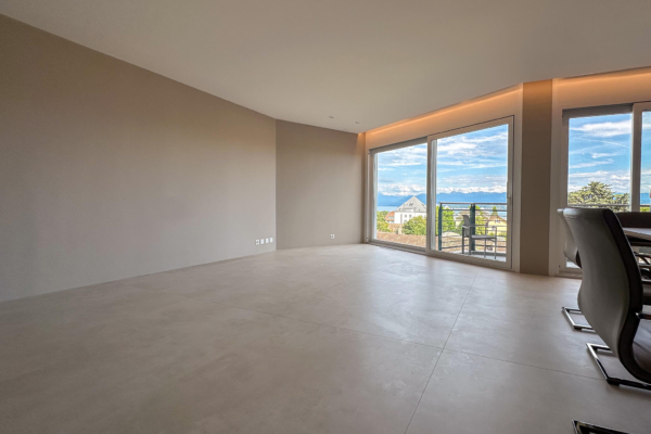 Séjour avec carrelage imitation béton, grandes baies vitrées et accès au balcon, vue imprenable sur Nyon, rénovation d'appartement