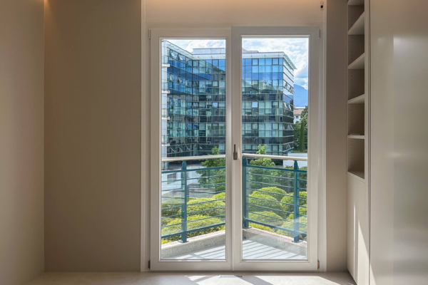 Chambre épurée avec carrelage imitation béton, porte-fenêtre donnant sur un balcon, rénovation d'appartement à Nyon