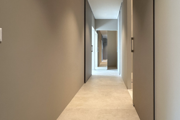 Porte de salle de bains moderne dans un couloir avec carrelage imitation béton et éclairage doux, appartement rénové à Nyon