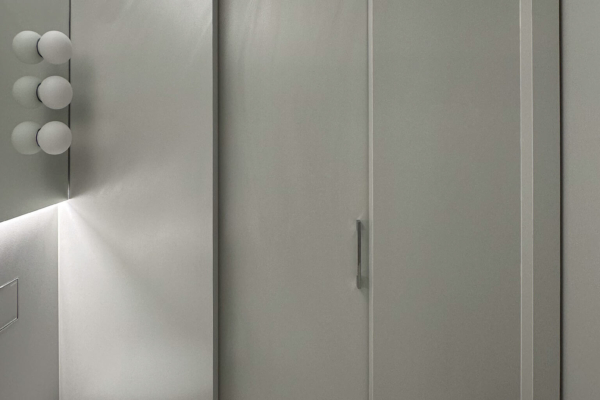 Porte de salle de bains dans un cadre moderne avec mur texturé en carrelage Iris Ceramica Luce gris clair et poignée discrète, rénovation à Nyon