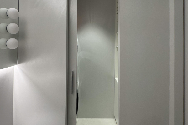 Porte desalle de bains avec vue sur un espace buanderie éclairé menant à un autre espace, murs en carrelage Iris Ceramica Luce gris clairs texturés, rénovation à Nyon